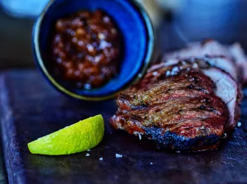 Gehobeltes Steak mit Limette und Saucenbecher.