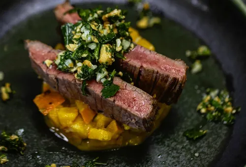 Steakscheiben mit Kräutern auf Gemüse.