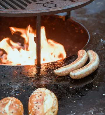 Würstchen grillen über offenem Feuer draußen.