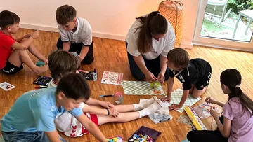 Kinder basteln mit einem Erwachsenen drinnen.