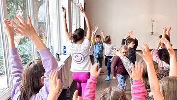 Kinder und Lehrer machen Yoga drinnen.
