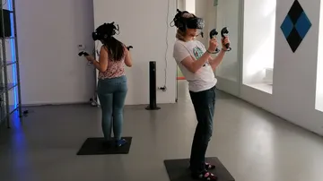 Zwei Personen nutzen VR-Headsets in einem Raum.