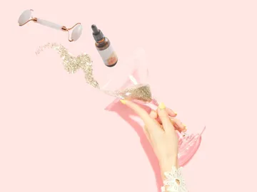 A glass is filled with glitter on a pink background.