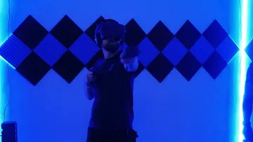Person mit VR-Headset in neonbeleuchtetem Raum.