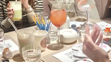 People holding drinks at a table gathering.