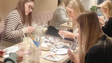 Women painting glass in cozy cafe.