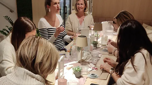 Women crafting at a wooden table together.