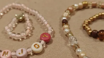 Beaded bracelets spelling 'JOY' on a table.