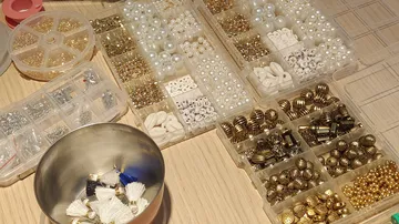 Various beads organized in containers on table.