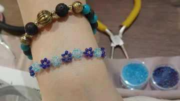 Beaded bracelet on wrist, pliers in background.