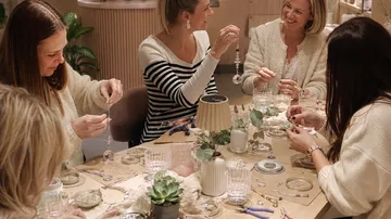 Women making crafts around a table.