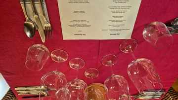 Upside-down wine glasses on red tablecloth.