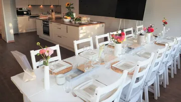 Dining table set with flowers, near kitchen.