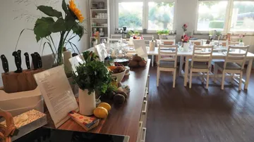 Kücheninsel mit Pflanzen, Esstisch im Hintergrund.