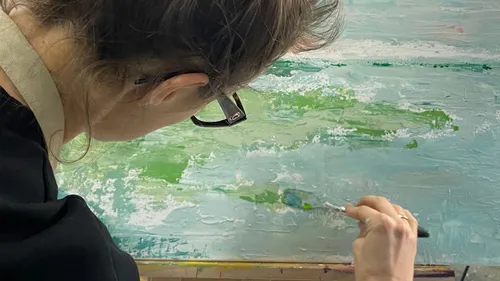 Person painting landscape on canvas.