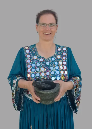Woman holding mortar and pestle, smiling.