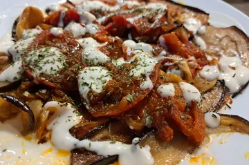 Auberginengericht mit Joghurt und Kräutern auf Teller.