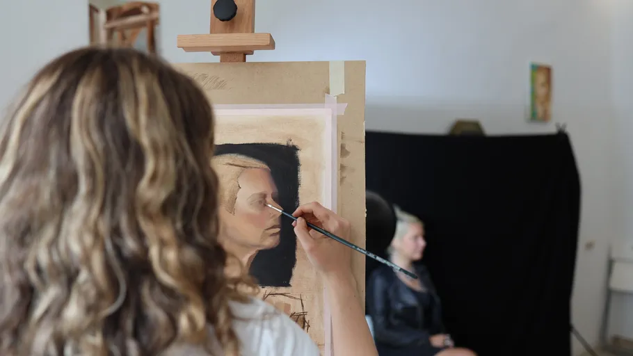 Artist painting a portrait in studio.