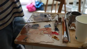 Kunstbedarf auf Tisch nahe Maler.