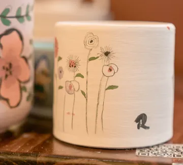 Flower pot painted with delicate flowers indoors.