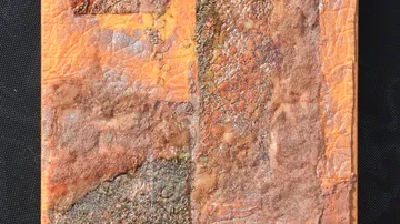 Abstract textured artwork in orange tones, indoors.