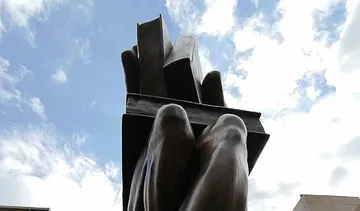 Bronzehandskulptur hält Bücher, draußen.