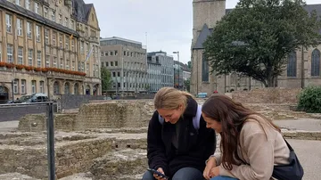 Two people looking at a phone outdoors.