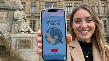 Woman showing phone with Duisburg app.