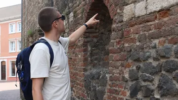 Mann zeigt auf alte Ziegelwand.