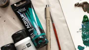 Malutensilien auf Tisch, Kunstwerk in der Nähe.