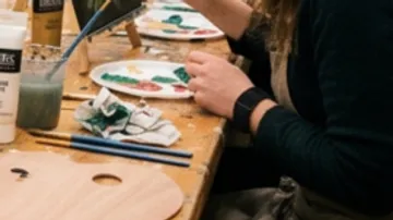 Person painting with brushes at a table.