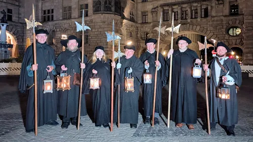 Group holding lanterns outside historic building.