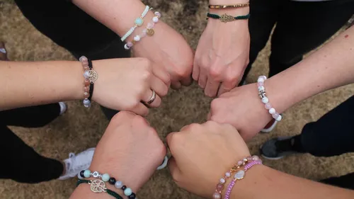 Six people showing bracelets outdoors.