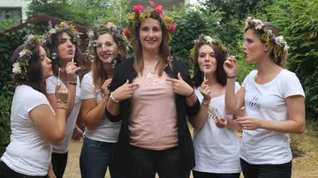 Women blowing bubbles, wearing floral crowns outdoors.