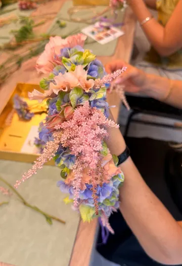 Hands holding a colorful flower arrangement.