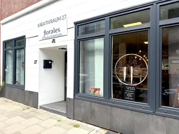 Schaufenster mit großen Fenstern und Schild außen.