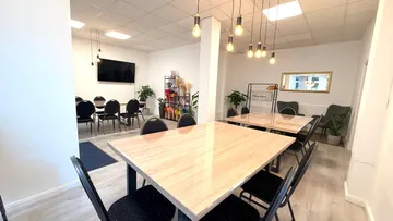 Meeting room with tables, chairs, decorative plants.
