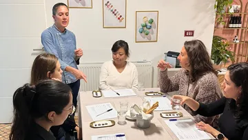 Chef instructing group around a table.