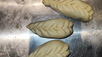 Drei Teigtaschen auf Metalloberfläche.