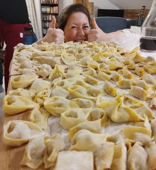 Frau zeigt Daumen hoch hinter hausgemachter Pasta.