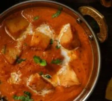 Curry mit Paneer in Metallschale serviert.