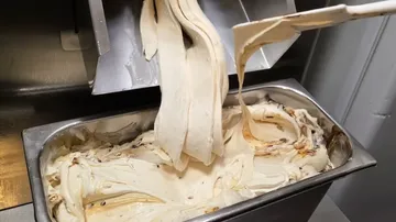 Ice cream dispensed into metal container.