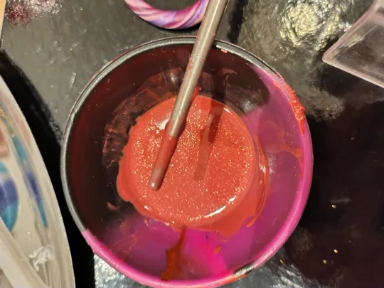 Rote Farbe in einer lila Tasse gerührt.