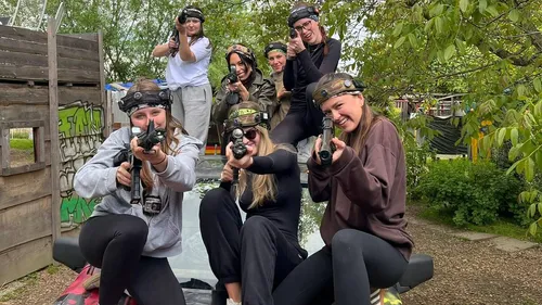 Gruppe spielt Lasertag im Freien, lächelnd.