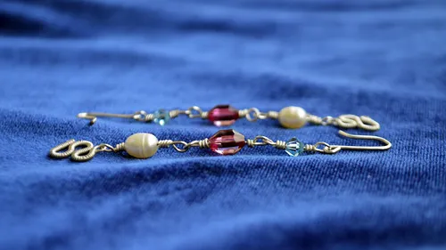 Beaded earrings resting on blue fabric.