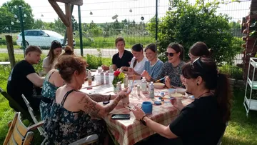 Menschen bemalen Keramik im Freien am Tisch.