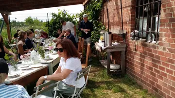 Menschen essen draußen an einem langen Tisch.