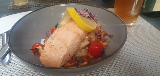 Lachsgericht mit Pilzen und Tomaten, Zitronengarnierung.