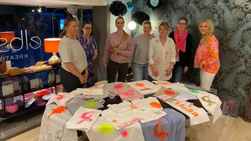 Gruppe posiert mit bemalten Textilien im Studio.