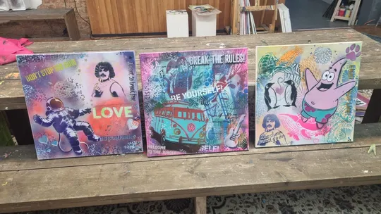 Drei Graffiti-Kunstwerke auf einem Holztisch platziert.